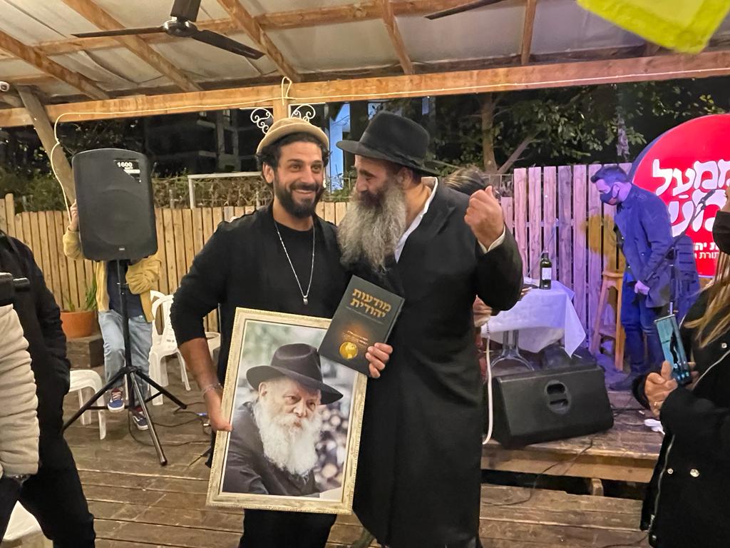 הרב יובל ברנס מעניק לאביב את תמונת הרבי שליט"א מלך המשיח בצירוף רב המכר - מודעות יהודית